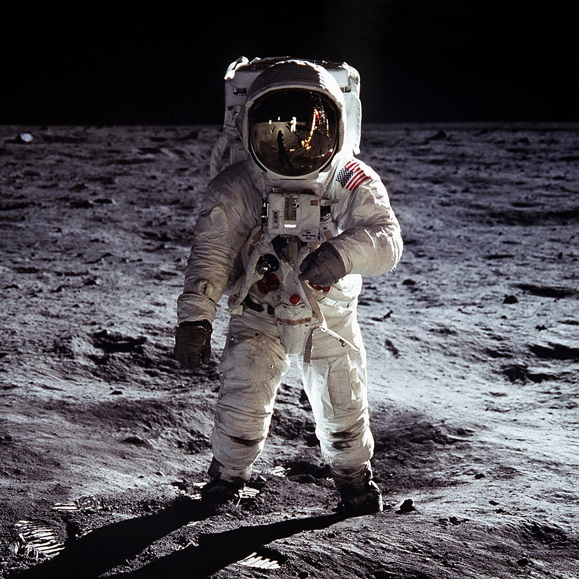 Astronaut i rymddräkt som står i sanden på månen. Horisonten är svart i bakgrunden.