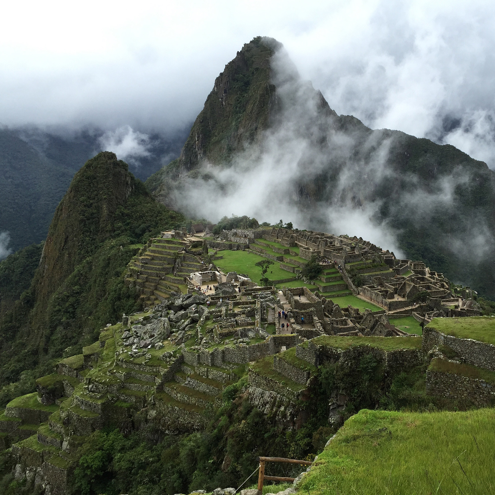 Machu Picchus ruiner med dimhöljda berg i bakgrunden.