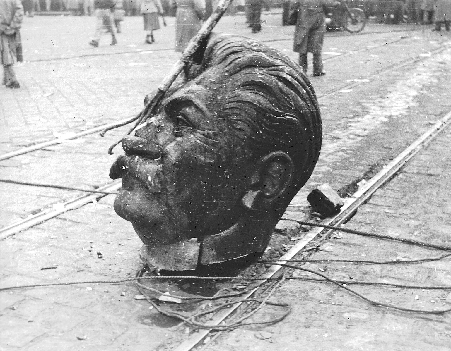 Avsågat jättelikt statyhuvud (Stalins) på ett torg.