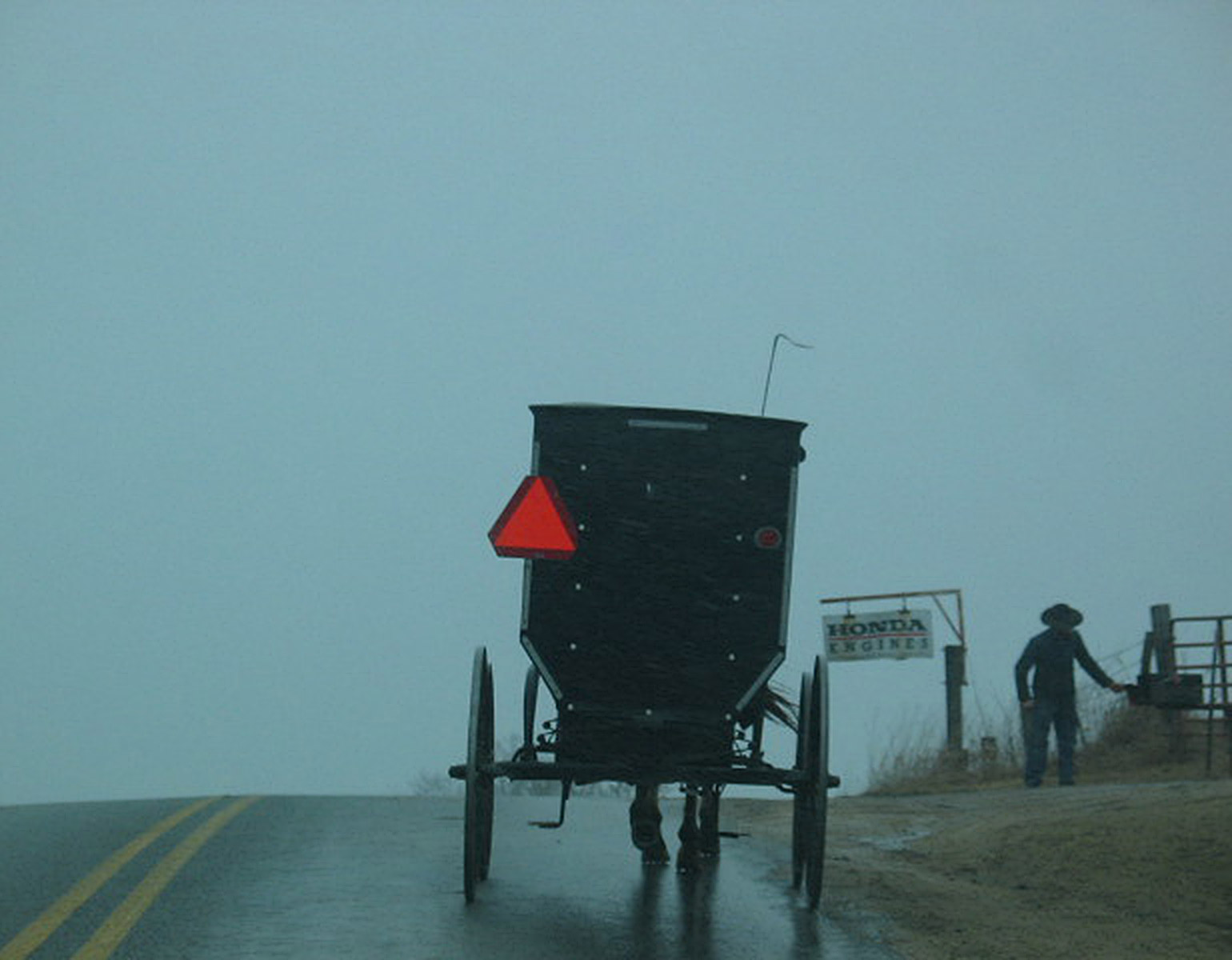 Häst och vagn på en regnig landsväg.