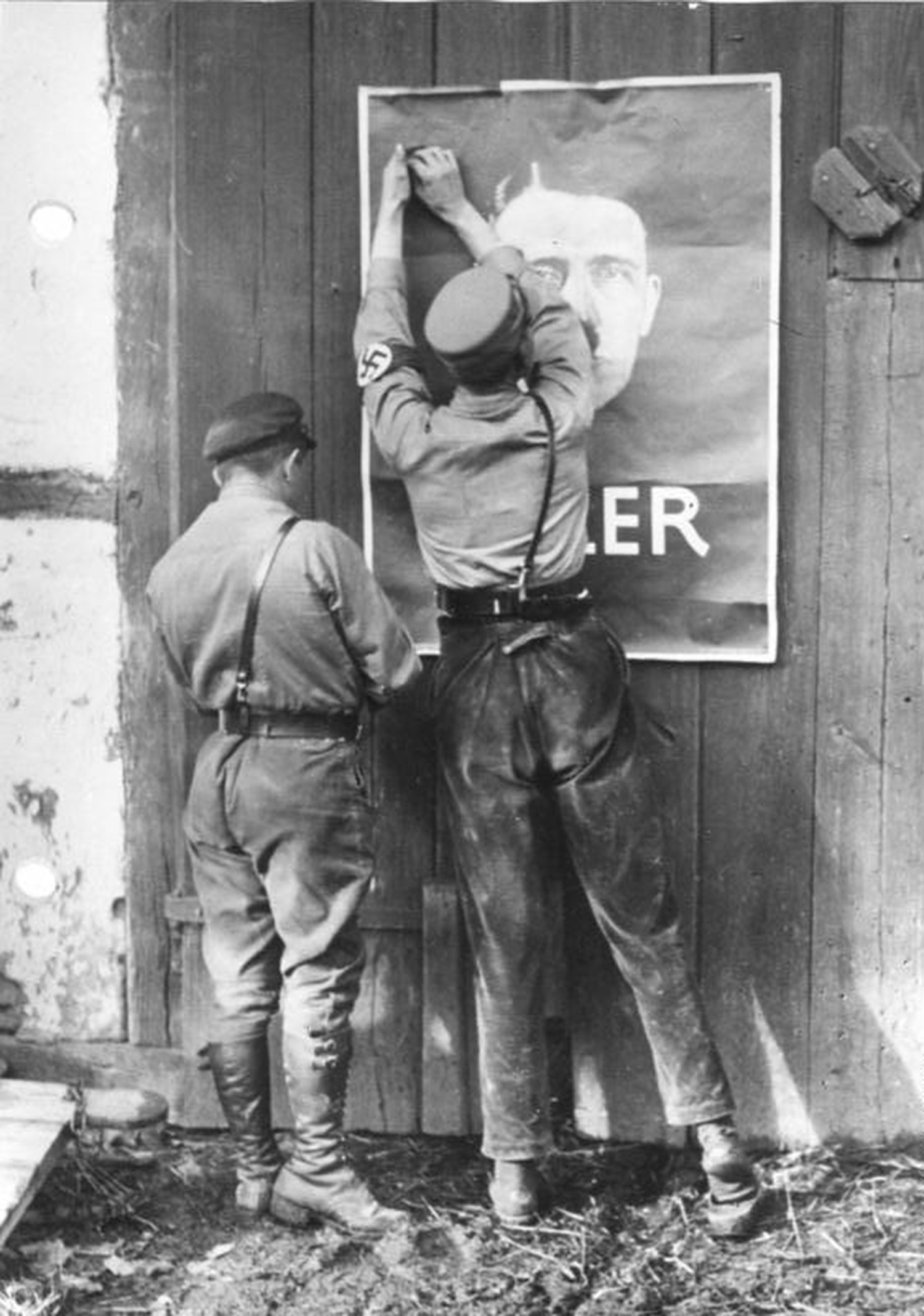 SA-män sätter upp en affisch på Hitler.