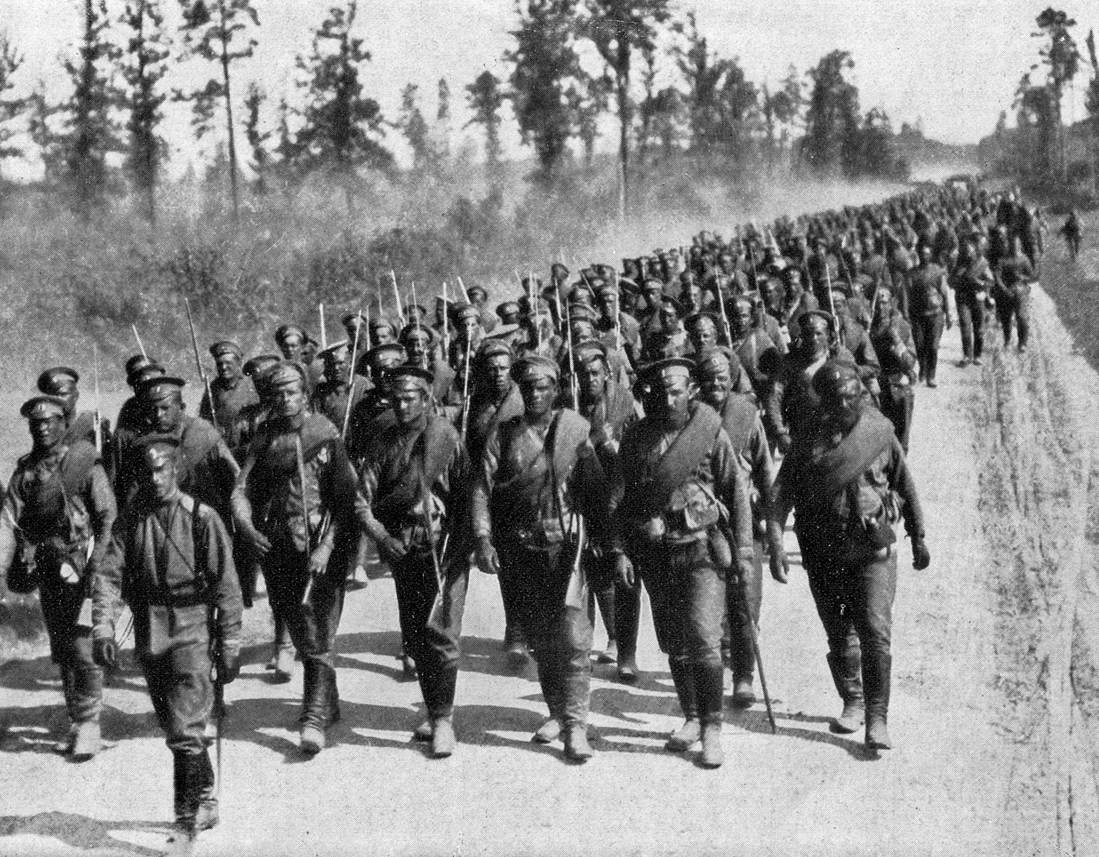 Hundratals ryska soldater marscherar på en grusväg i en skog.