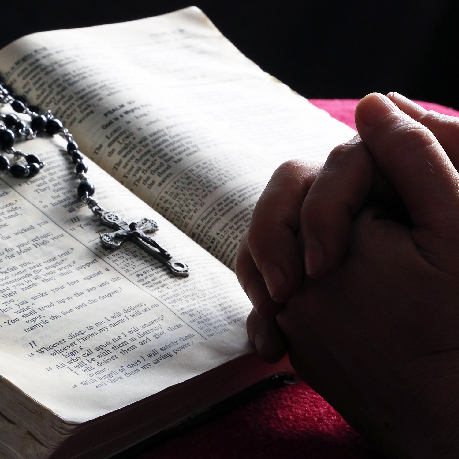 Händer knäppta i bön över en bibel.