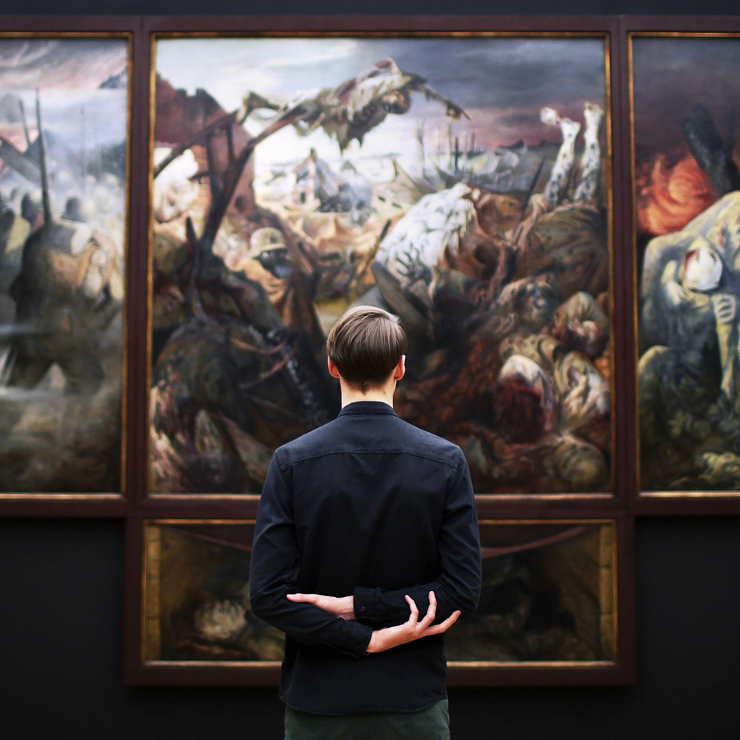 En ung man som betraktar en stor tavla (historisk målning) på ett museum.