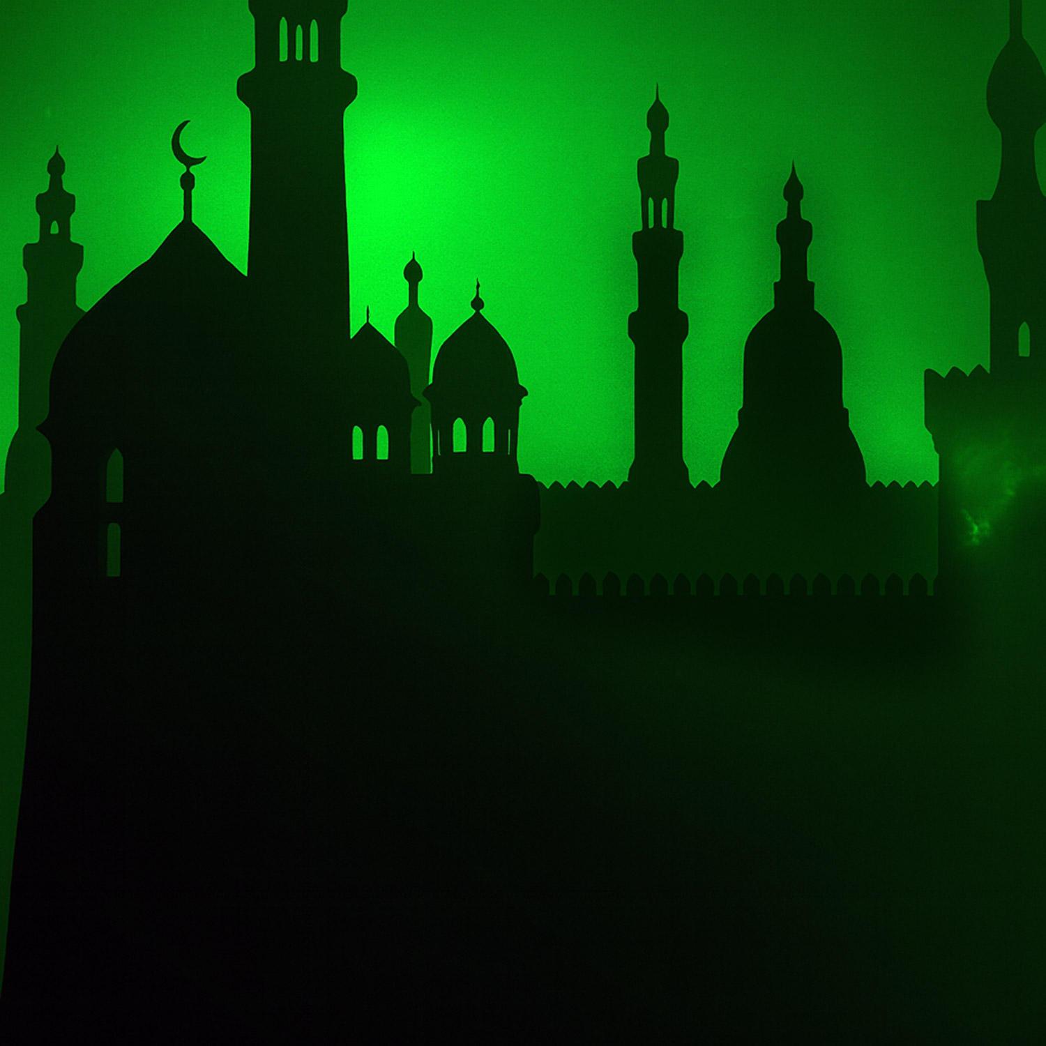 Siluett över muslim religiös bebyggelse - torn och minoreter. Grön himmel som bakgrund.