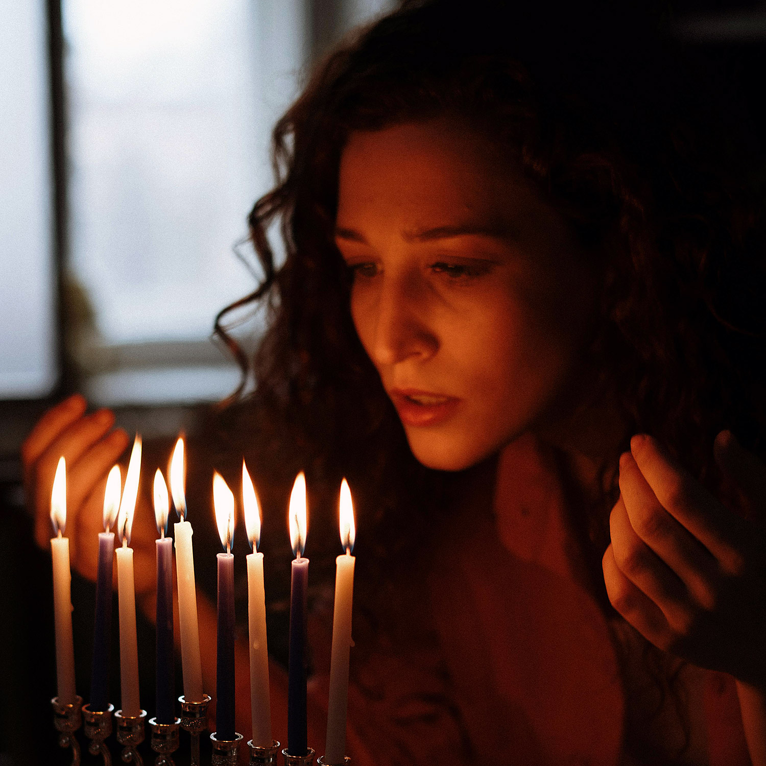 En judisk kvinna som tänder ljus på en ljusstake.