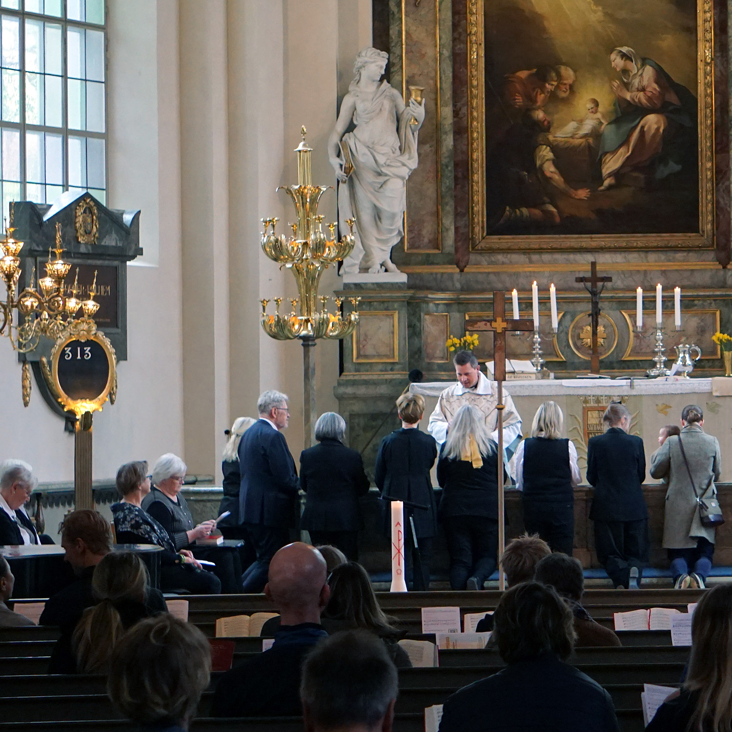 En grupp äldre människor tar nattvard i en kyrka.