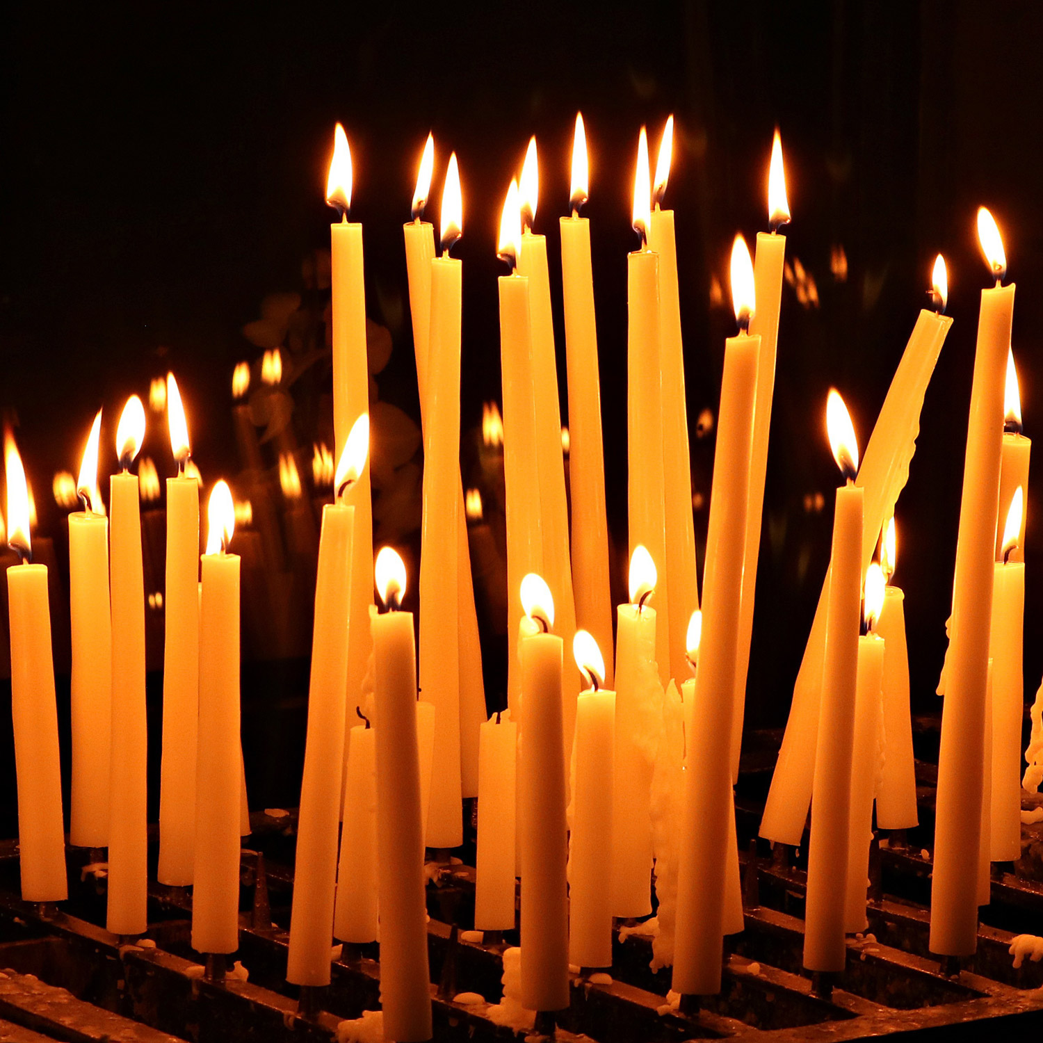 Brinnande gula stearinljus i en kyrka.