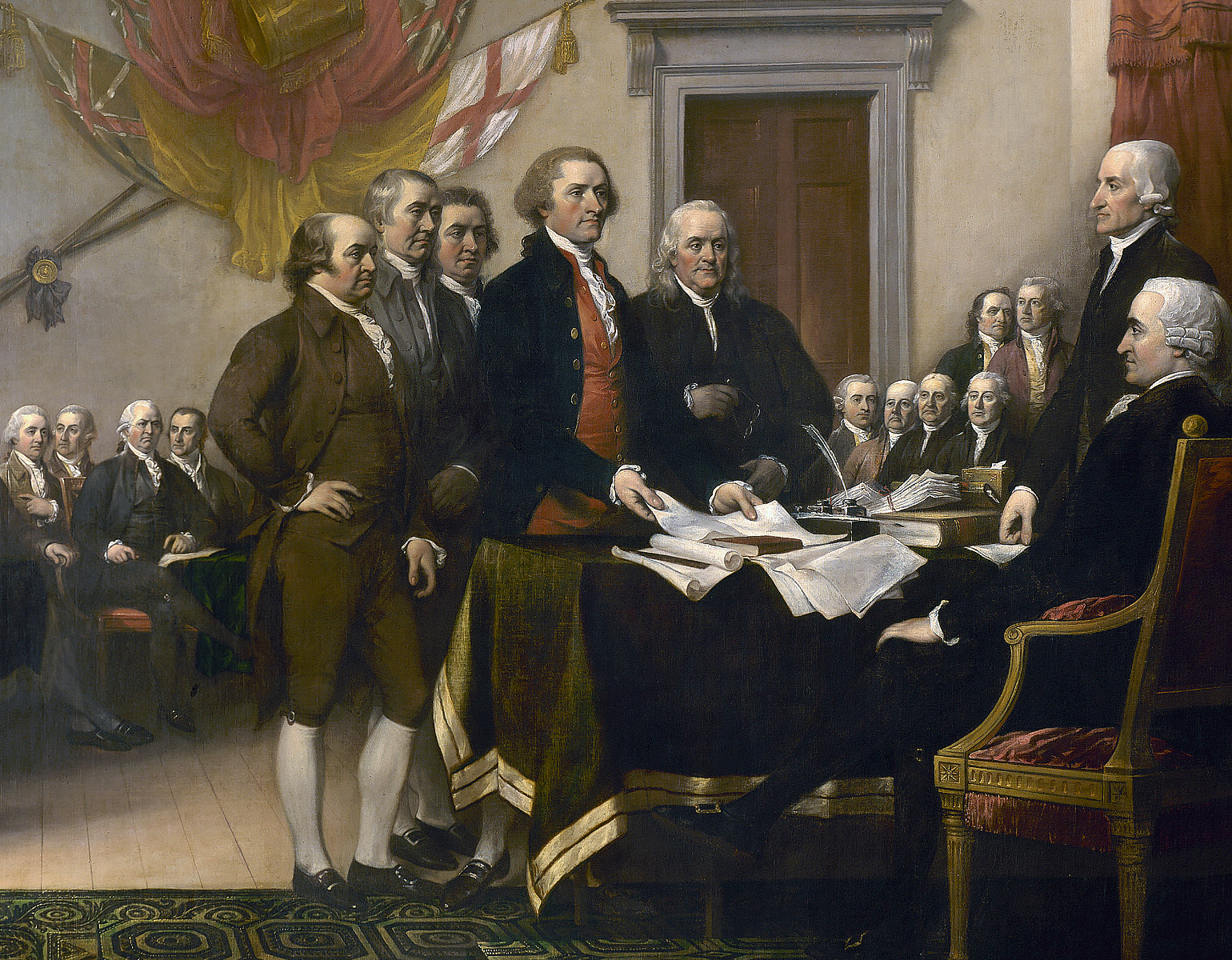 Sju personer runt ett bord inför en stor församling.