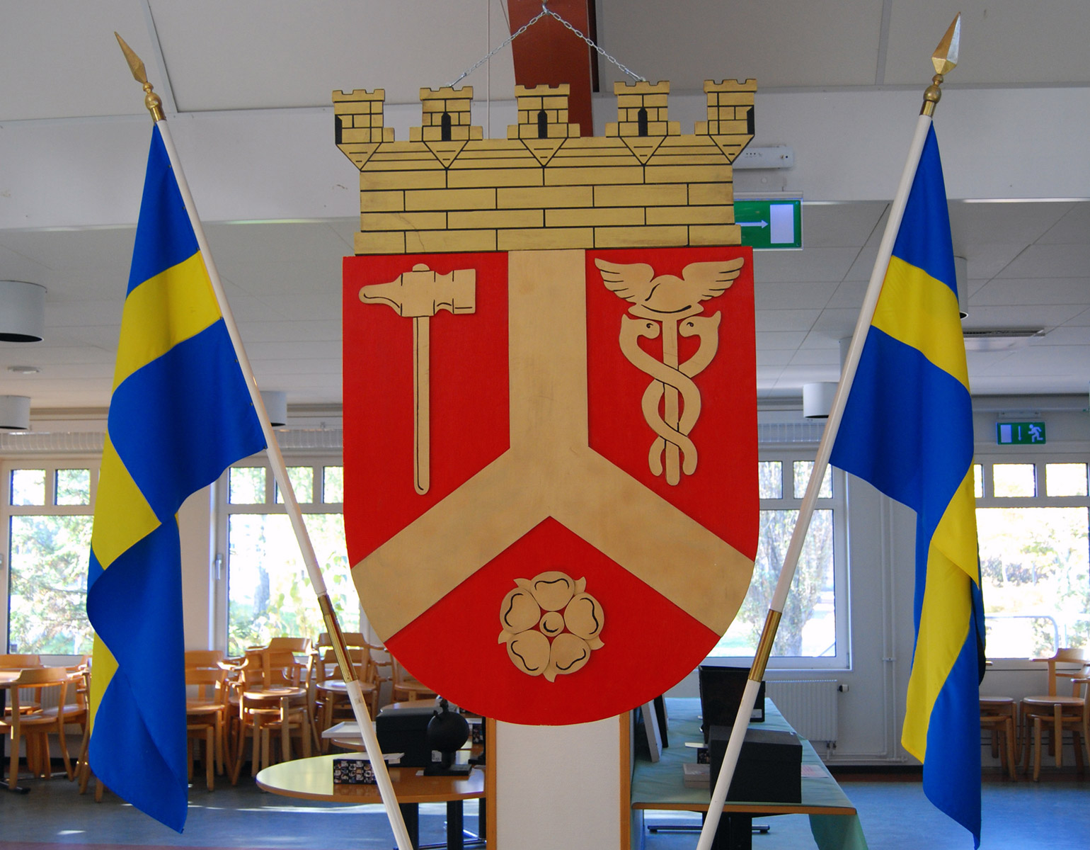 Kommunvapensköld med två flaggor bredvid.