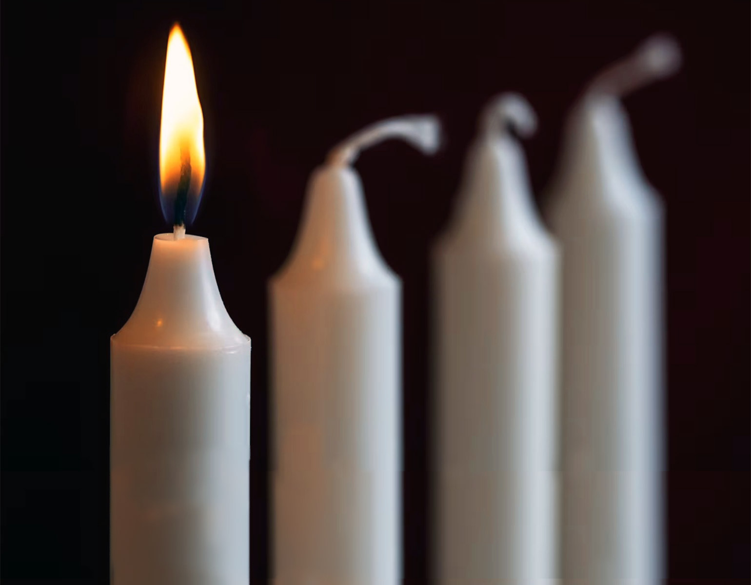 Ett tänt stearinljus i en ljusstake med fyra stearinljus.
