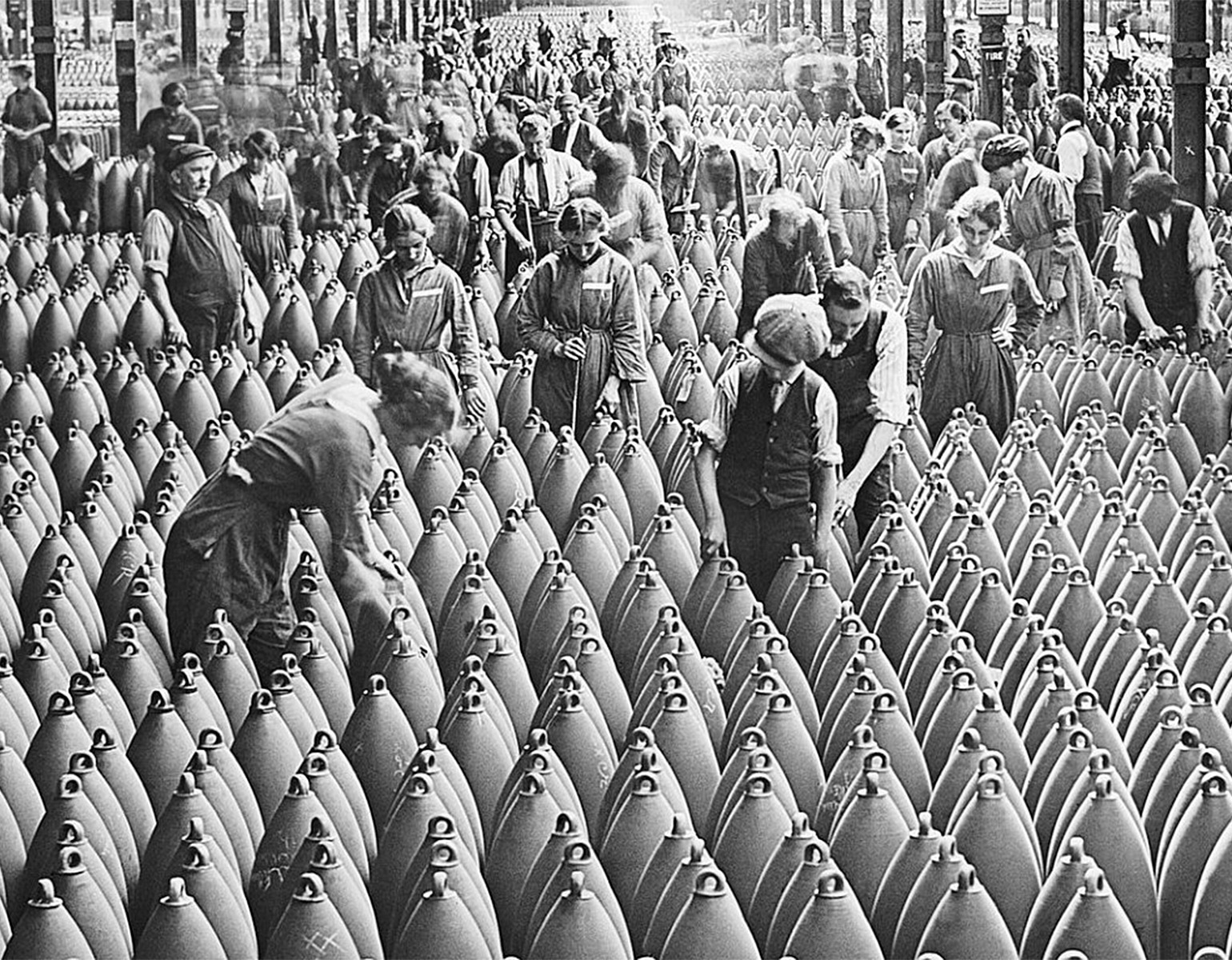 ett hundratal arbetare på ett jättelikt lagerlokalgolv där det står tunsentals granater staplade.