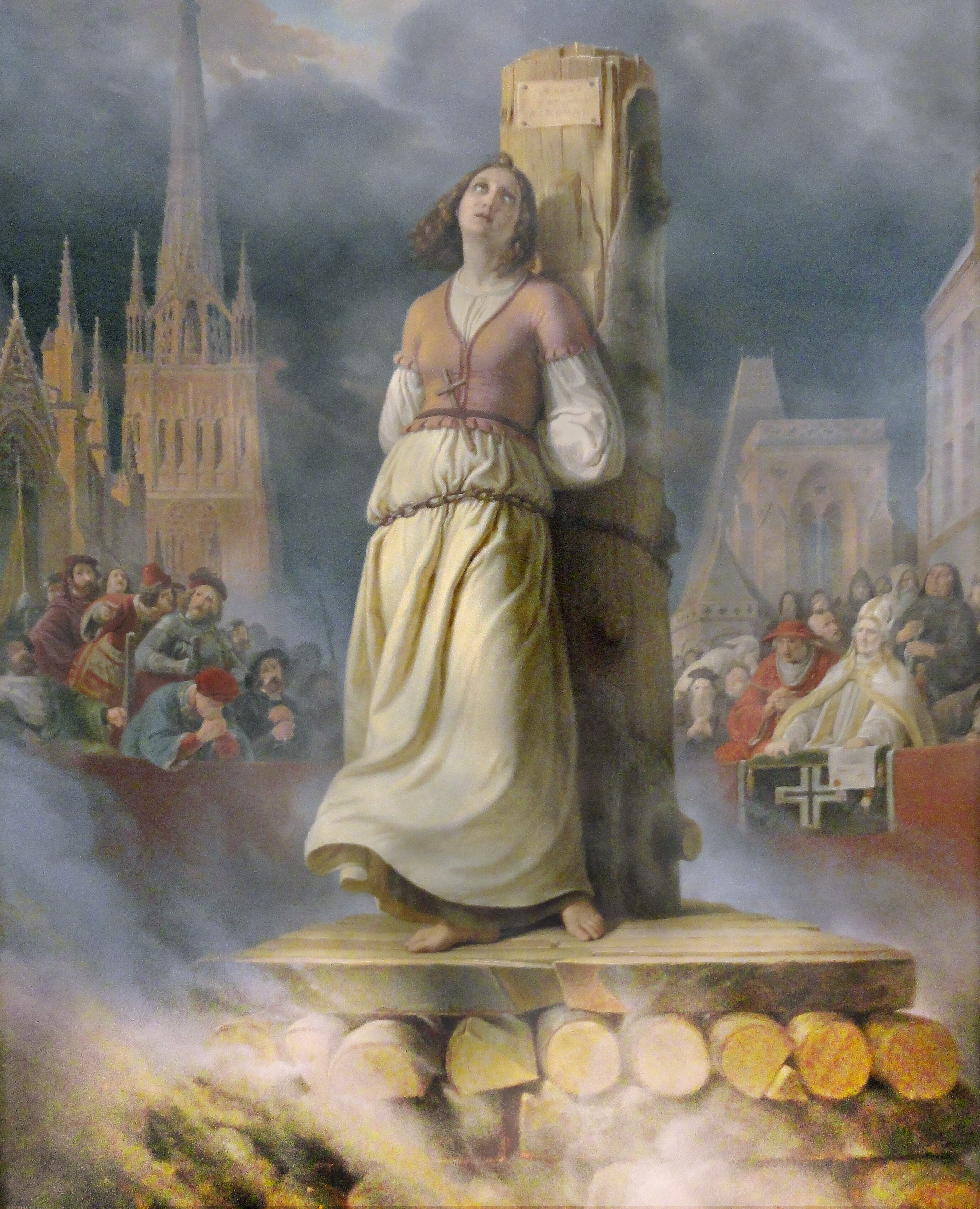 Kvinna bunden vid en påle på ett bål som antänds. En folkmassa är publik.