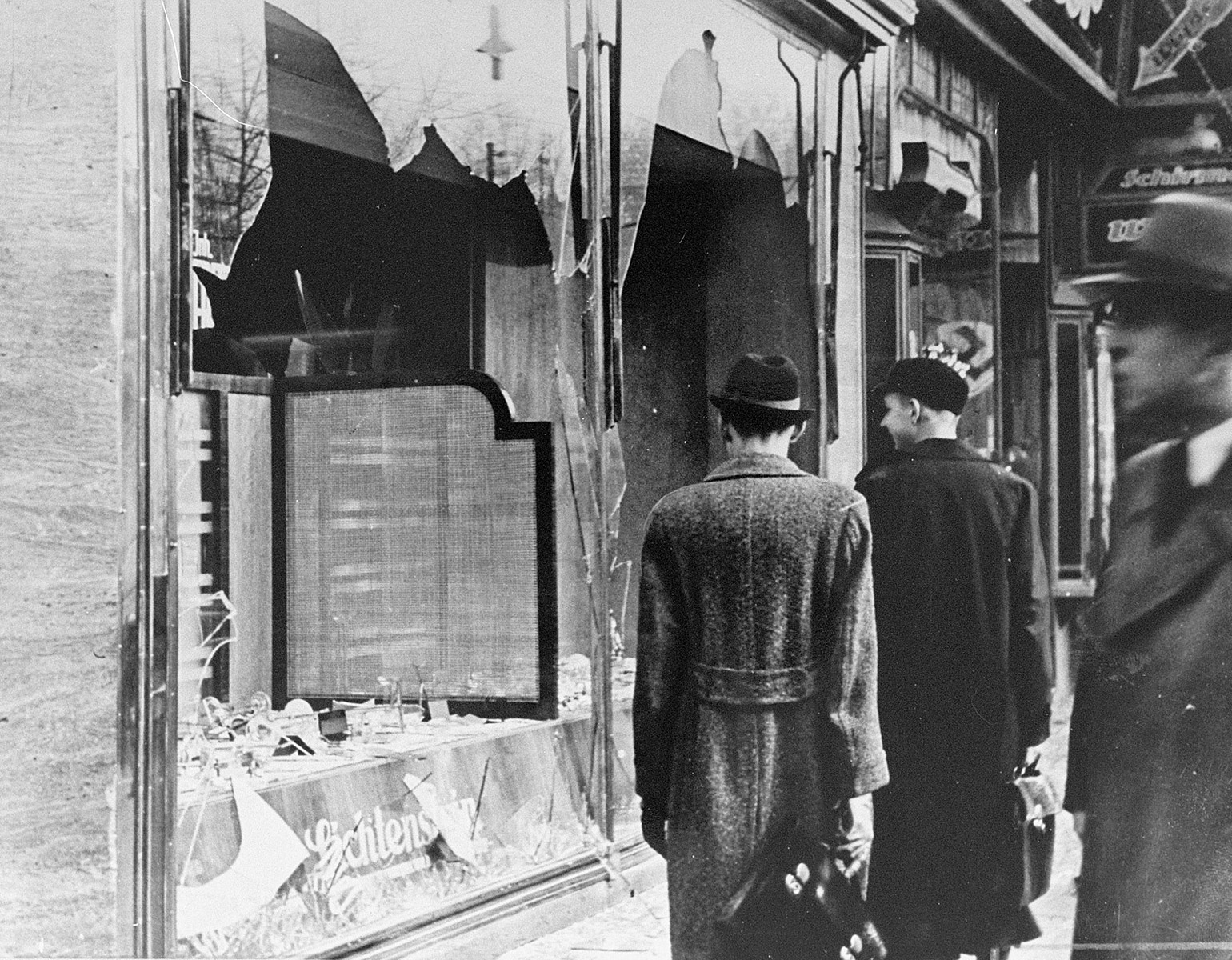 Krossade skyltfönster på en gata. Ett par går förbi.