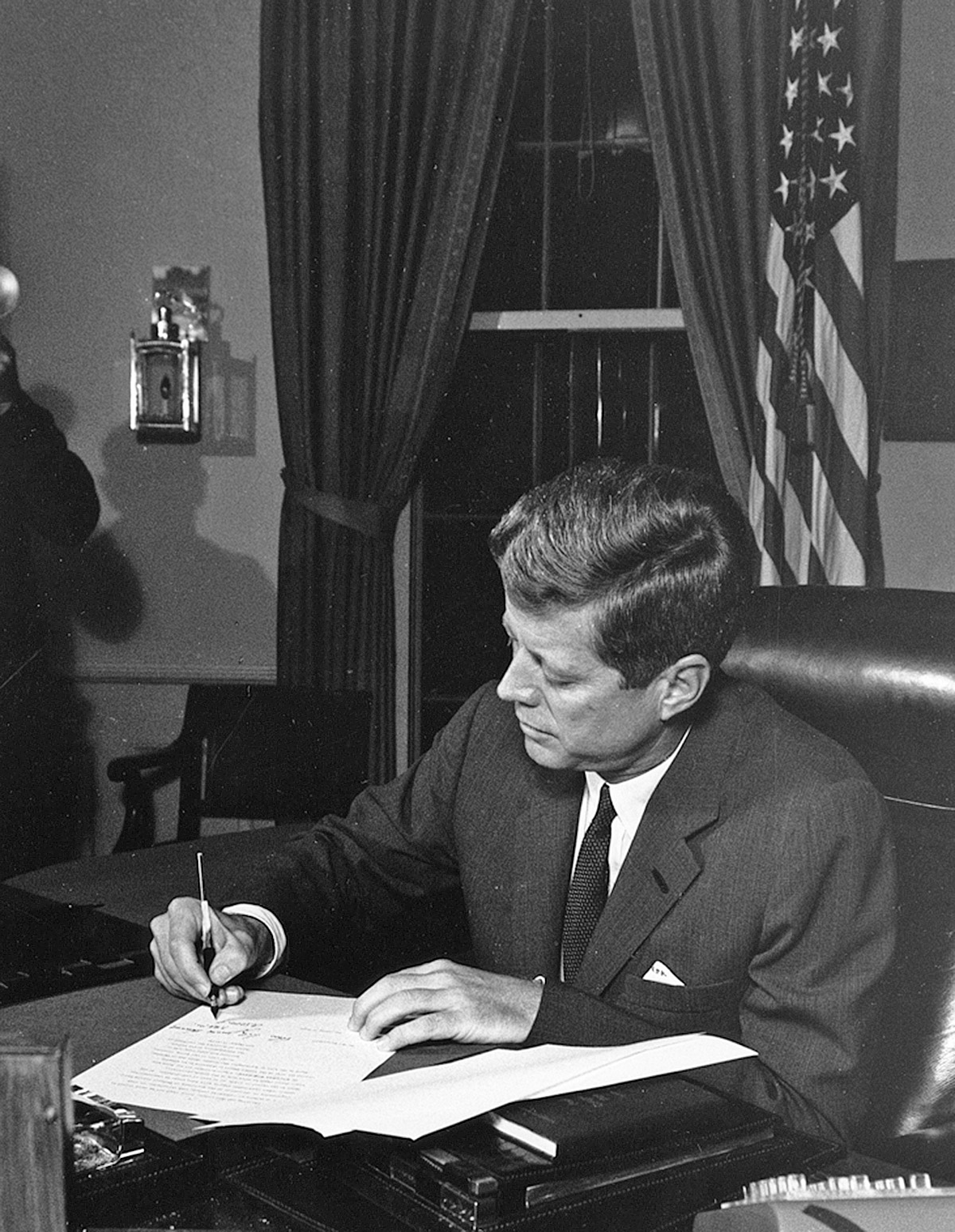 Kennedy skriver på ett dokument.