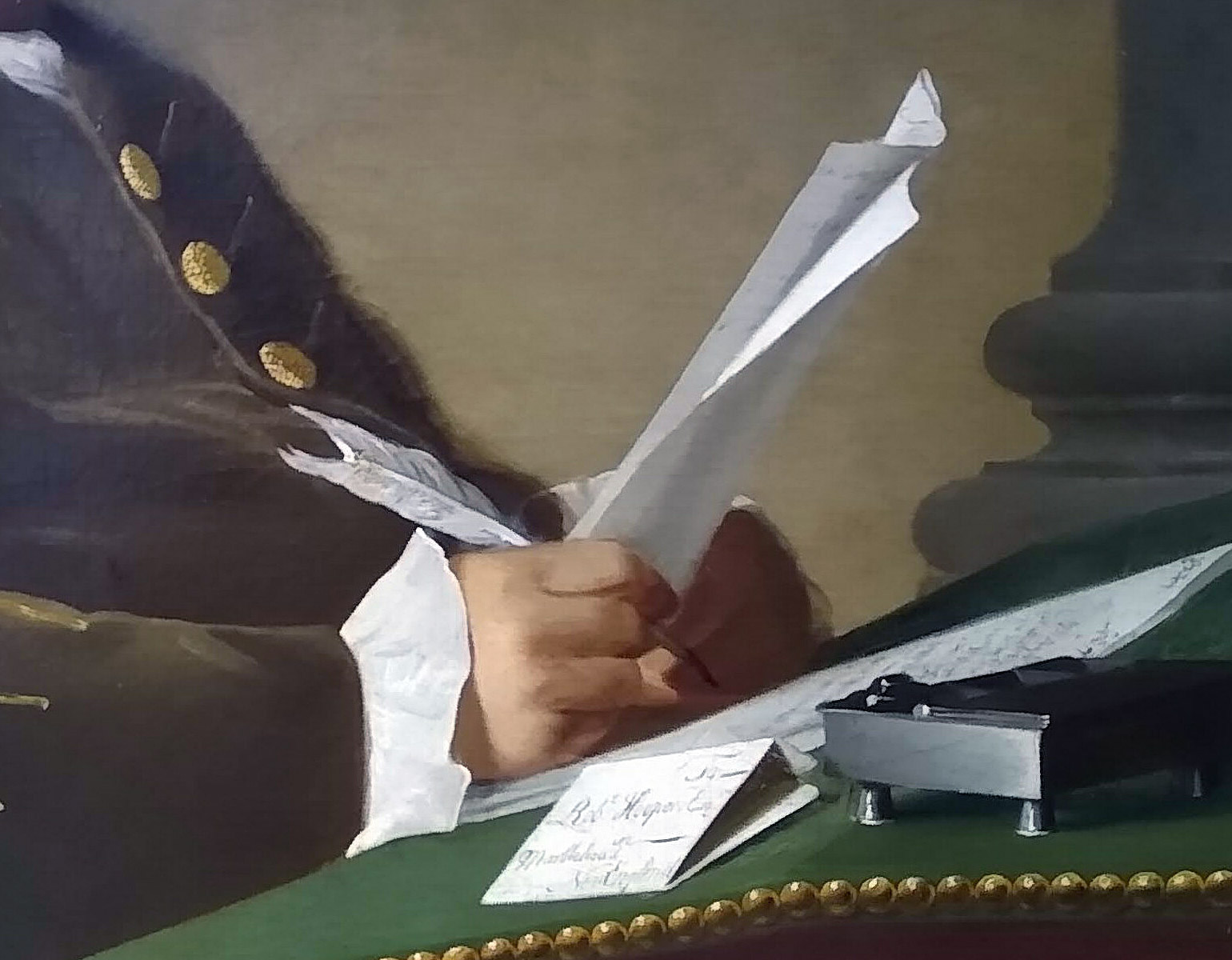 Skrivbord med en man som håller i ett papper och en gåspenna.