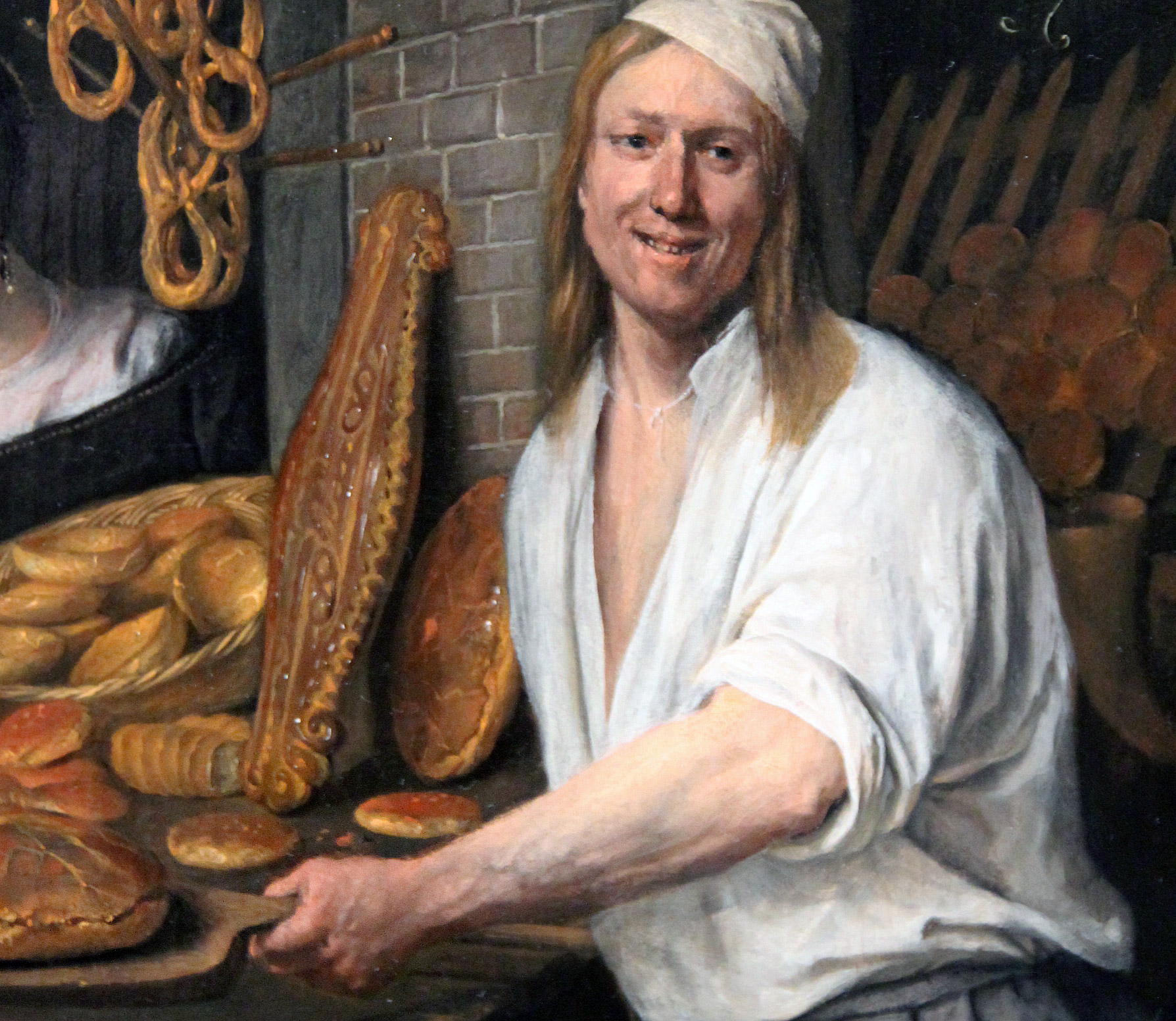 En bagare som poserar med sina bröd och bullar.