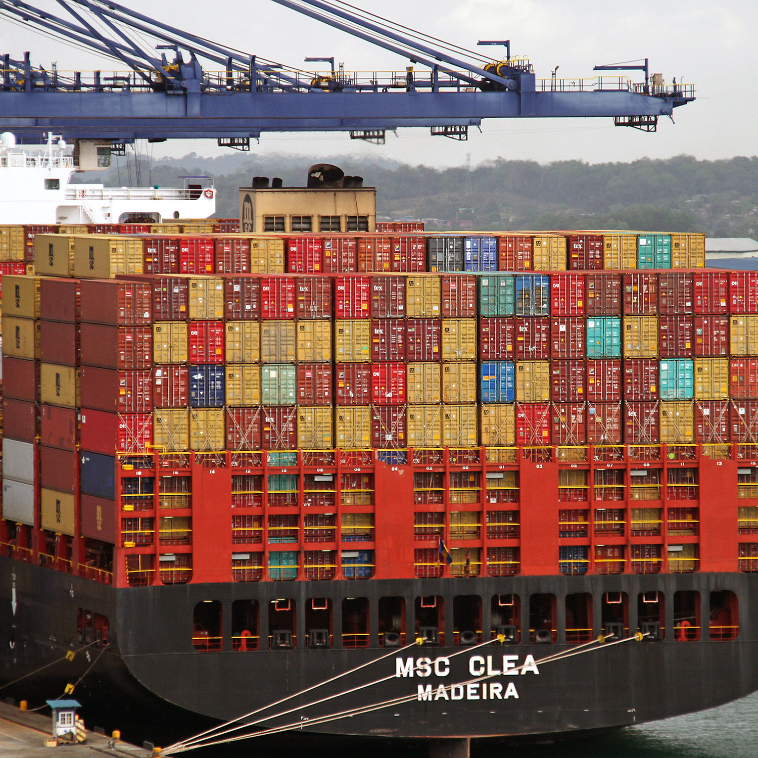 Del av ett enormt containerfartyg som lastas i en hamn.