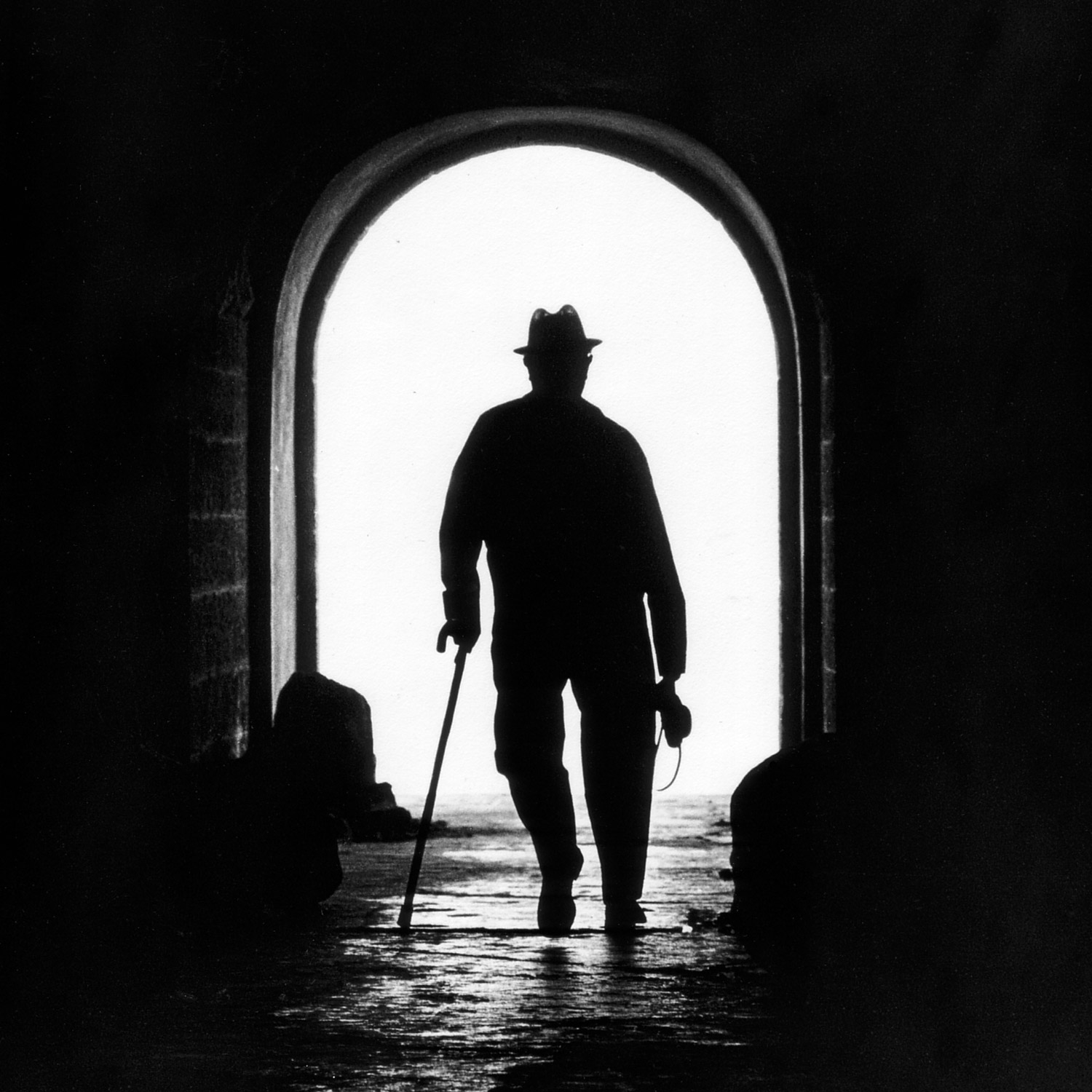 En man med käpp går genom en mörk tunnel.