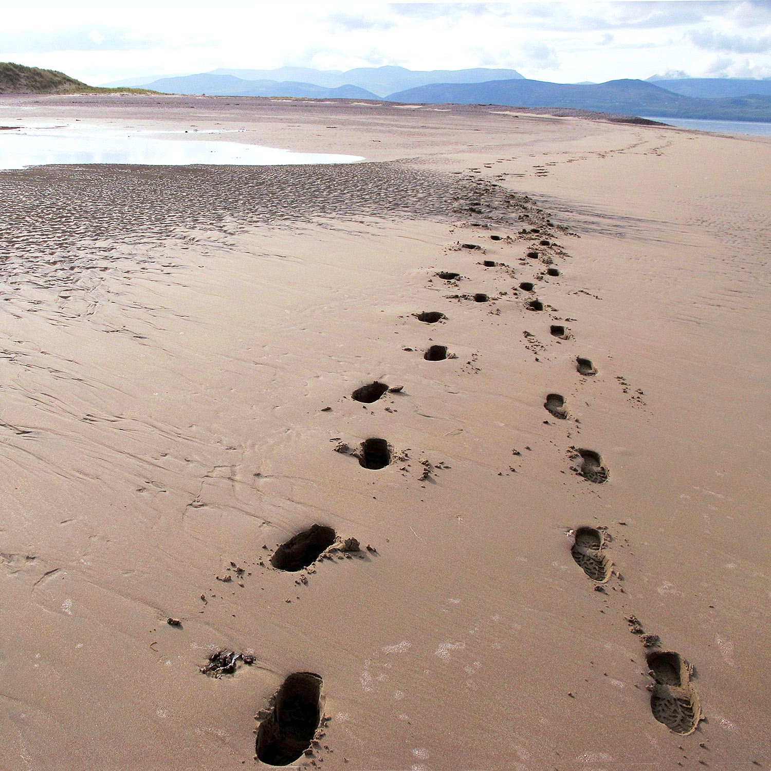 Fotspår på en öde ssandstrand.