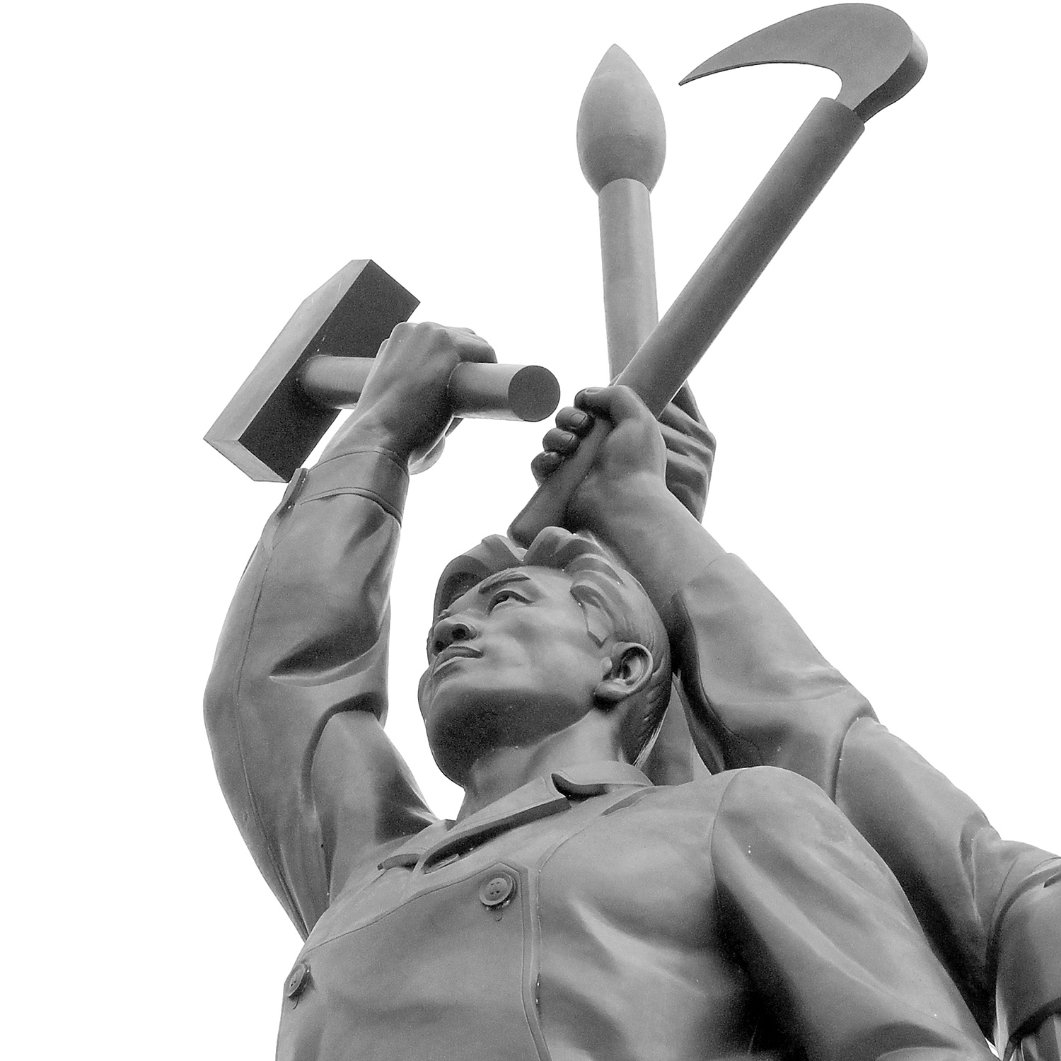 Kommunistisk staty i Nordkorea med män som håller en hammare och en lie i luften.